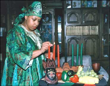 Woman Wearing a Uwole and Lighting Candles in a Kinara